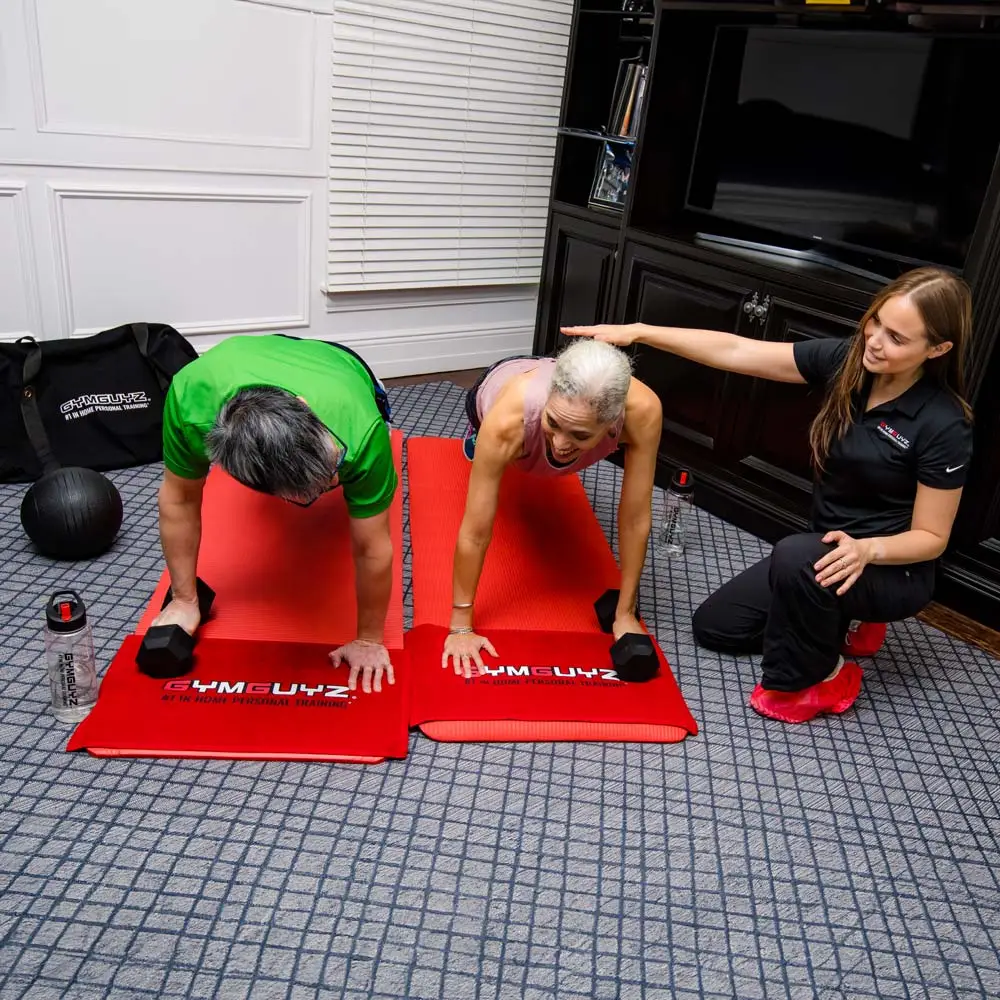GYMGUYZ In-Home Personal Training A couple working out at home with a certified personal trainer.