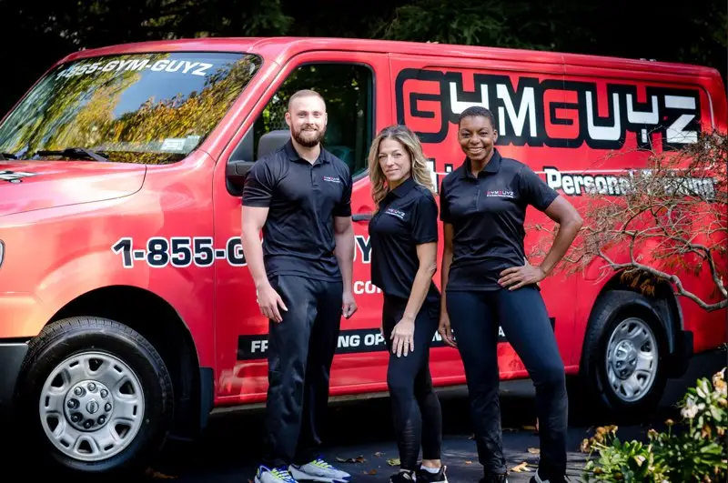 GYMGUYZ In-Home Personal Training Certified personal trainers in front of a red GYMGUYZ van.